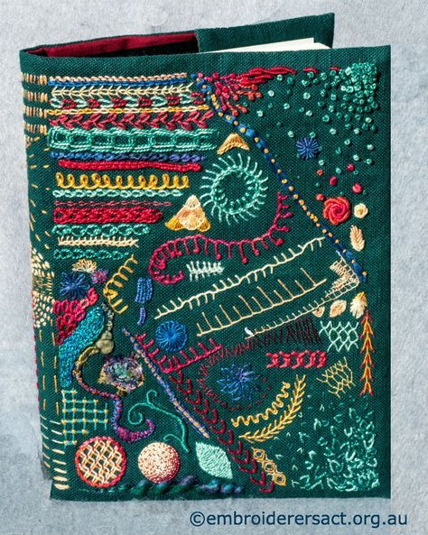 a green book with colorful embroidered designs on the front and back cover, sitting on top of a gray surface