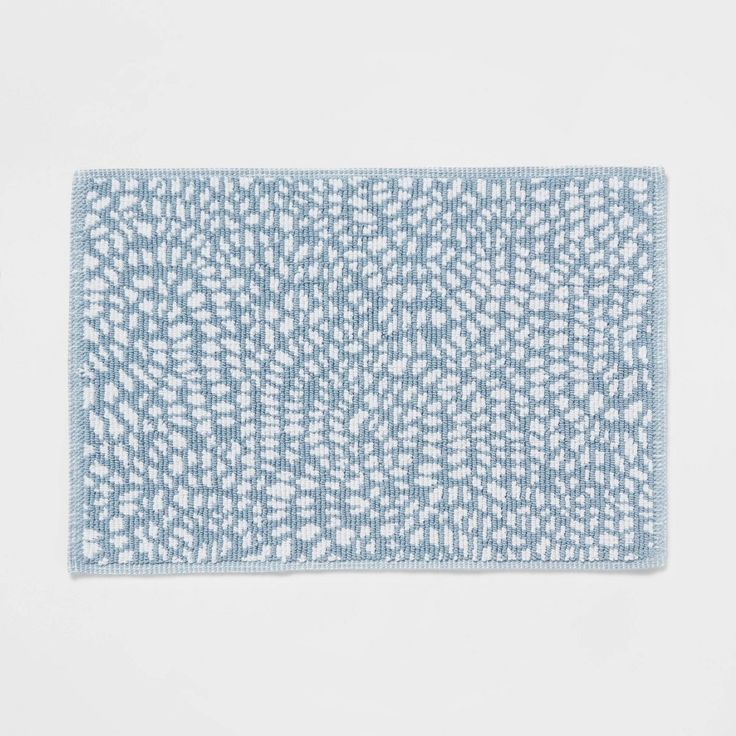 a blue and white bath mat on a white surface, with small dots in the middle