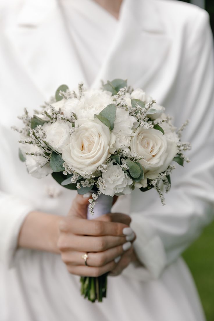 a bride holding a bouquet of white flowers