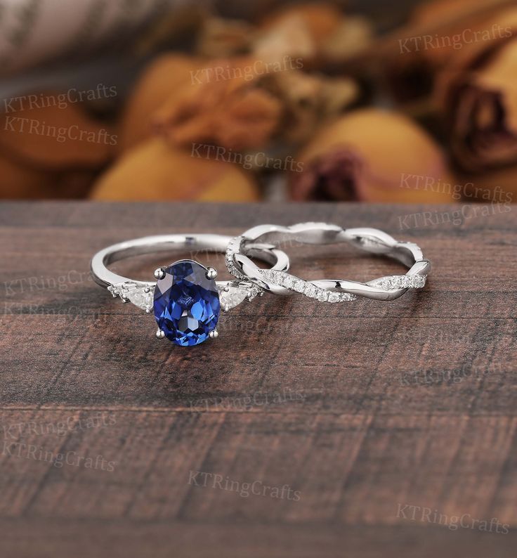 two wedding rings with an oval blue sapphire stone on the top and diamond accents around the band