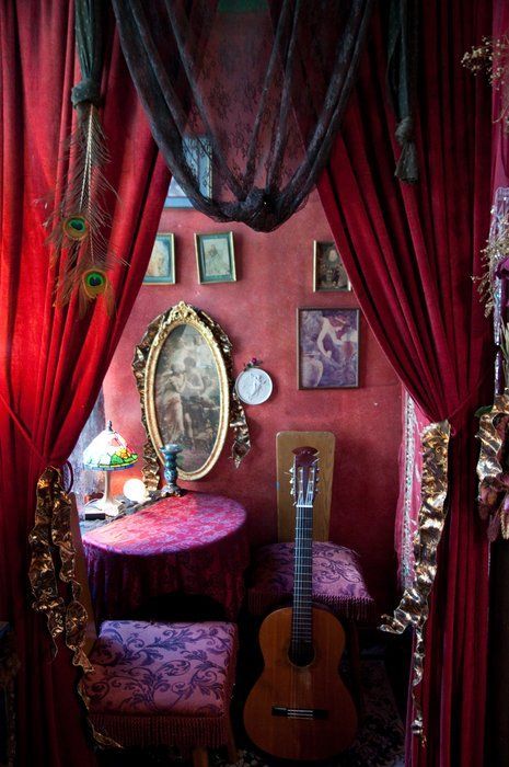 a room with red curtains and a guitar on the table in front of a mirror