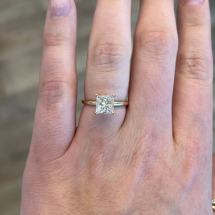 a woman's hand with a diamond ring on top of her finger, and the other hand holding an engagement ring