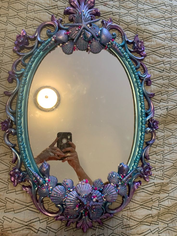 a woman taking a selfie in front of a mirror with seashells on it