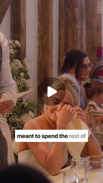 a woman covering her face while sitting at a table with other people in the background