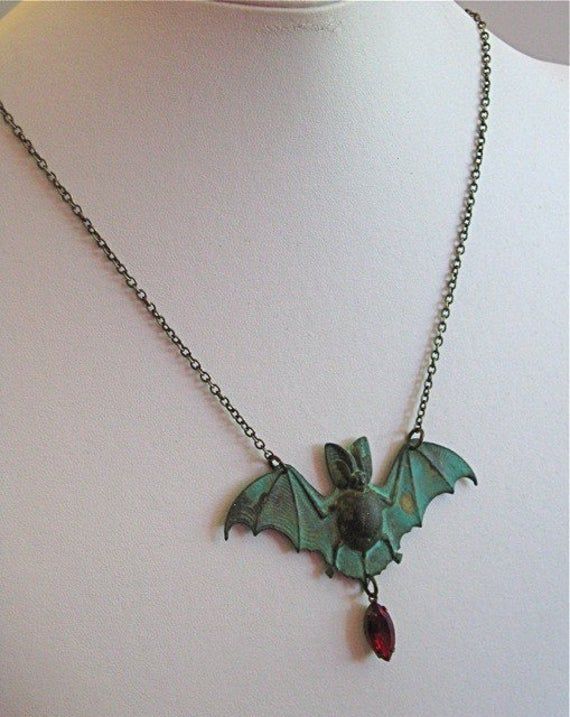 "Vampire Bat Necklace - Siam Faceted Crystal Glass Jewel in Antiqued Brass Setting dangles from a Verdigris Patina Brass Bat. The jewel looks like a droplet of blood. Bat measures just under 2.75\" wide x just over 1.25\" tall (excluding jewel) 24\" Brass Chain This is a stock photo. Each piece is unique. The verdigris will vary from the one pictured. For other bat designs: https://www.etsy.com/shop/mcstoneworks?ref=l2-shopheader-name&search_query=bat Be sure to check out my Patina Collectio Vampire Style Halloween Necklace For Jewelry Making, Handmade Vampire Jewelry For Halloween, Vampire Style Necklace For Halloween, Handmade Vampire Style Party Necklace, Collectible Vampire Jewelry For Halloween, Handmade Vampire Style Jewelry For Cosplay, Vintage Costume Necklaces For Halloween, Handmade Vampire Jewelry For Cosplay, Handmade Vampire Style Necklace For Gift