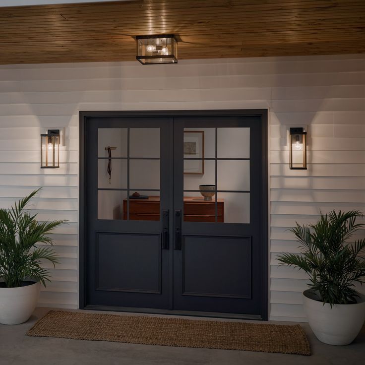 two potted plants are sitting on the front steps of a house with double doors