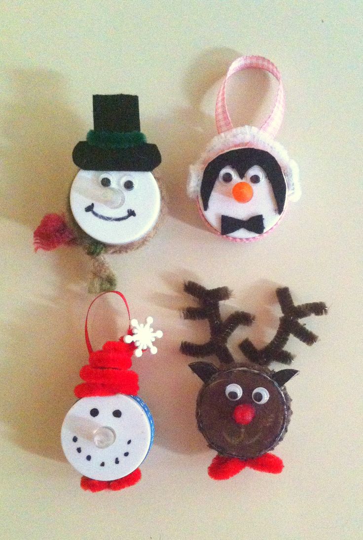 four christmas ornaments made to look like snowman, penguin, and reindeer faces on a white surface