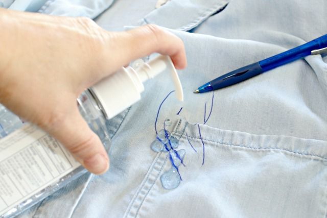 a person's hand is writing on the jeans with a pen and ink bottle