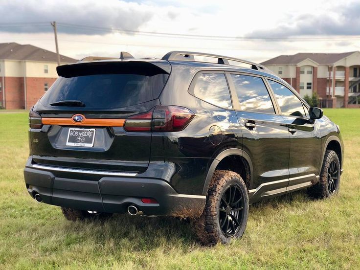 the rear end of a black suv parked in a field