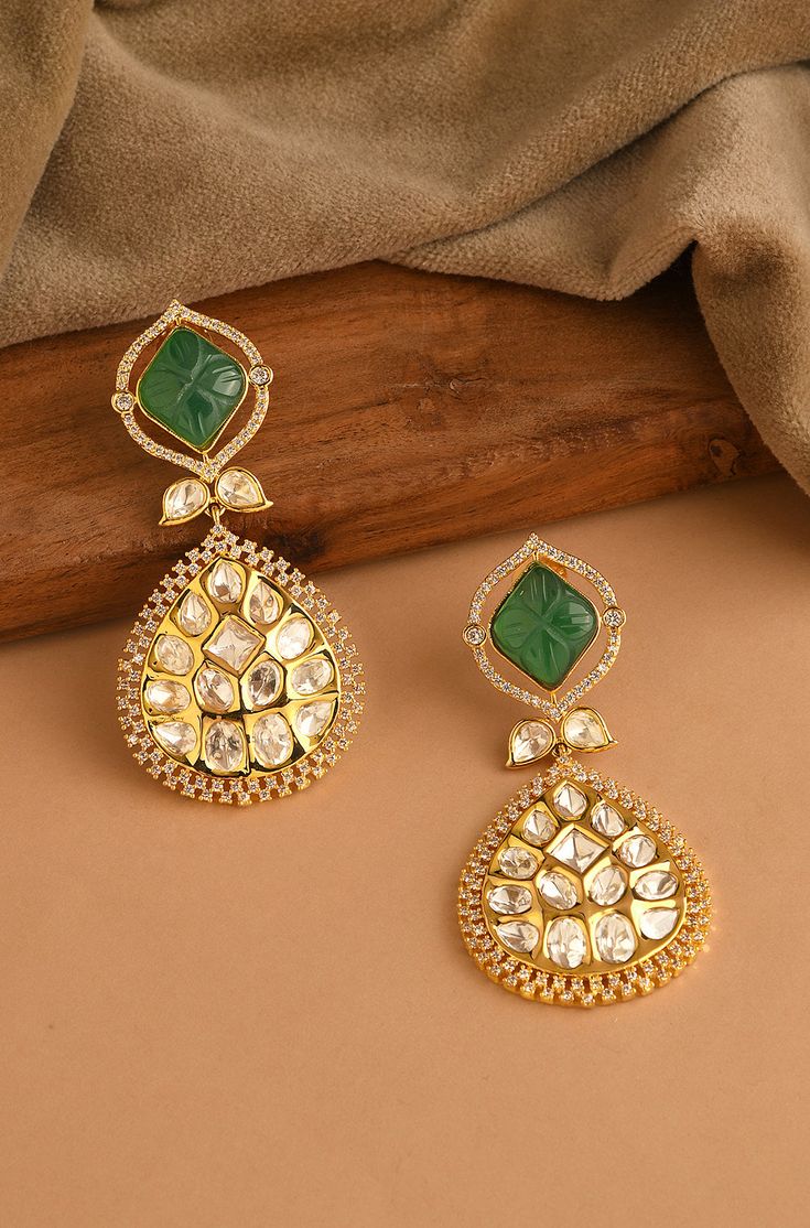 Indulge in sophistication with these Kundan earrings, featuring a striking emerald stone surrounded by sparkling diamonds, exuding timeless elegance and charm. Finish: 22KT Gold Plating Material: Brass, Kundan, Carved Emerald Stone Color: Gold, Green Size: One Size Closure Type: Push Back Box Contains: 1 Pair of Earrings Emerald Earrings Indian, Carved Emerald, Hand Jewelry Rings, Chain Braid, Artificial Jewelry, Kundan Earrings, Jewelry Indian, Emerald Earrings, Emerald Stone