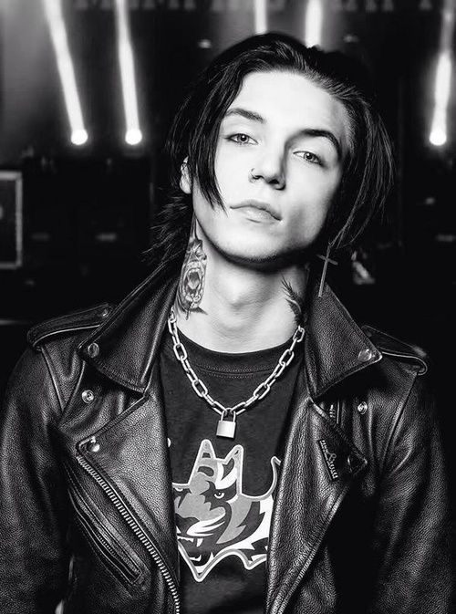 a man with long hair and piercings wearing a leather jacket is posing for a black and white photo