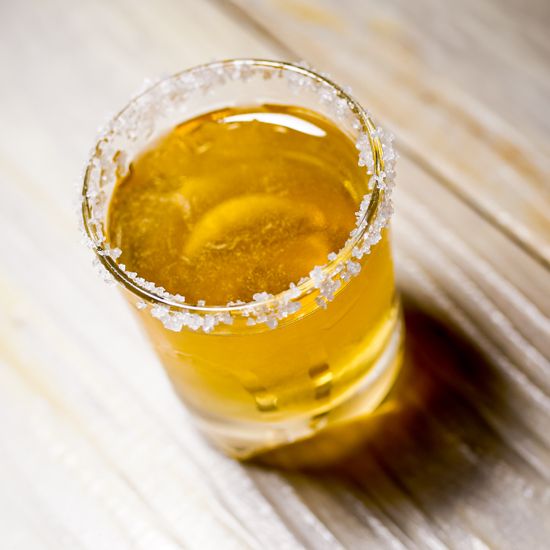 a glass filled with liquid sitting on top of a wooden table