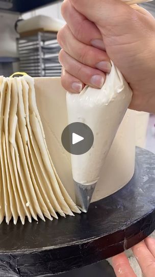 a person is using a knife to decorate a cake with white icing on it