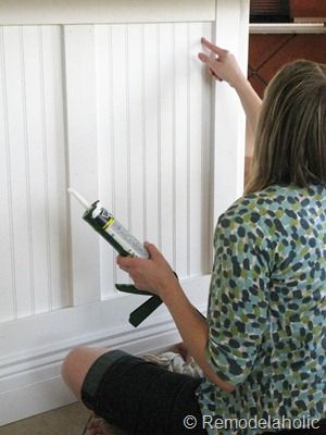 a woman sitting on the floor painting a wall