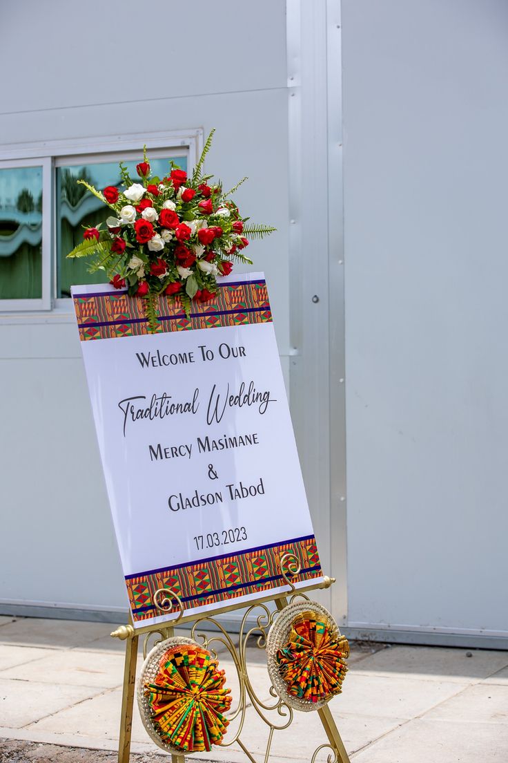 a sign that is sitting on the side of a building with flowers in front of it