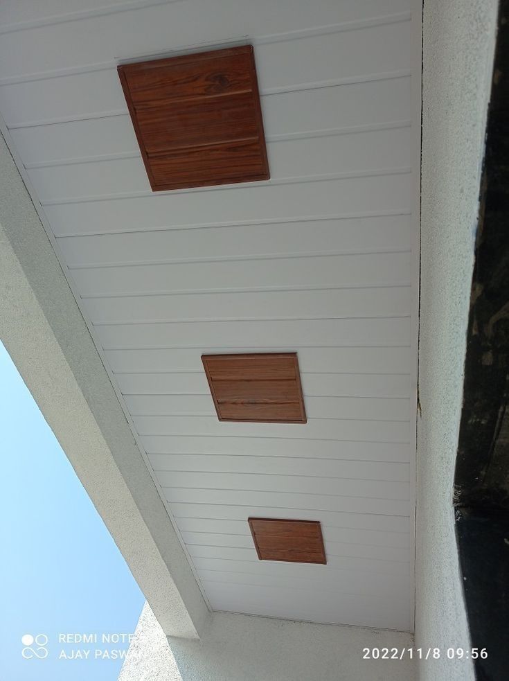 three square wooden windows on the side of a white building with wood trim around them