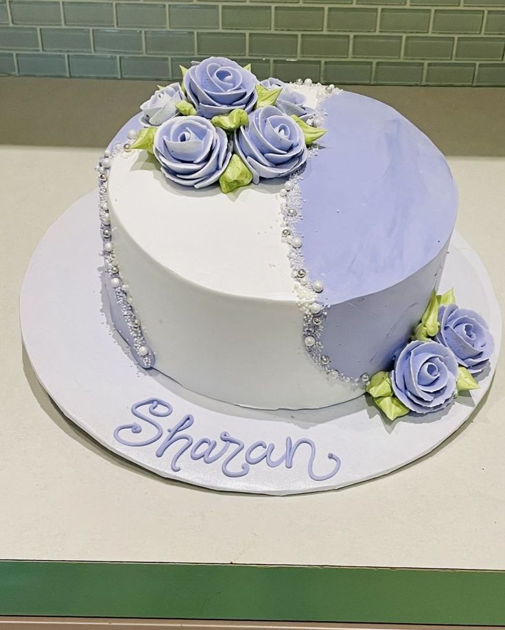 a white cake with blue frosting and purple roses on top that says sharon