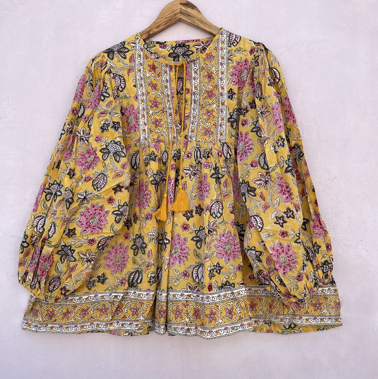 "DESCRIPTION yellow pink flower printed blouse and tops / Henley neckline with tassel blouse / long sleeve summer blouse Indian (Jaipur) Traditional Hand Block Printed Dresses for summer vacations, beaches wear, party wear, and more occasions to wear this dresses. PRODUCT DETAILS: Long sleeve, round neck, blouse FABRIC: soft and breathable cotton cambric WASH CARE:  wash in cold water, air dry in shade.. SLEEVE LENGTH - 22 INCH Size chart is mentioned in images. Size chart is given of the garment not the person wearing the garment We will be happy to customize according to your measurements. Message us for custom wholesale orders. Color of given picture may slightly vary due to sunlight, screen's resolution and camera focus. also you can write for more information to my email (laxmiexport0 Tassel Blouse, Round Neck Blouse, Blouse Indian, Flower Print Blouse, Summer Vacations, Indian Blouse, Summer Blouse, Printed Dresses, Blouse Long Sleeve