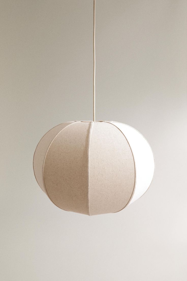 a white lamp hanging from a ceiling in a room with beige walls and flooring