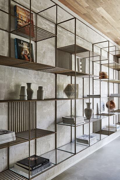 the shelves are filled with vases, books and other decorative items on display in front of a concrete wall