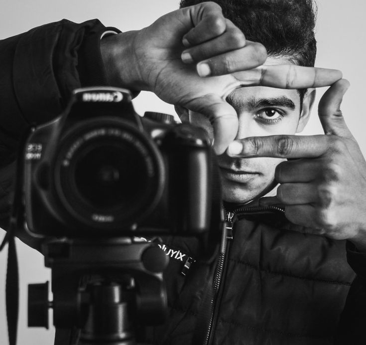 a black and white photo of a man holding his hand up to the camera's eye