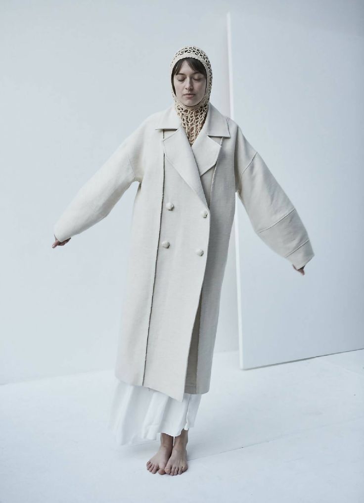 This sweeping statement coat exudes oversized elegance with its wide lapels leading to a romantic deep V neckline. Falling just above the ankles, the Snegurochka Cream Wool Hemp Shell Buttons Coat is both cozy and sophisticated. Made from a blend of durable hemp and wool fibers, its sturdy structure is punctuated with uniquely handcrafted ceramic shell buttons. Lined.Composition 40% Hemp 60% Wool and it´s undyed.Lining 100% viscoseTrimming 100% ceramic glazed handmade shell buttonsSizesOversize. Oversized Long Outerwear In Winter White, Elegant Oversized Beige Wool Coat, Chic Long Wool Coat For Spring, Beige Oversized Wool Coat With Lapel Collar, Oversized Beige Shawl Collar Outerwear, Oversized Wool Outerwear In Winter White, Oversized Beige Pea Coat With Lapel Collar, Oversized Cream Sweater Coat For Spring, Winter White Long Outerwear For Spring