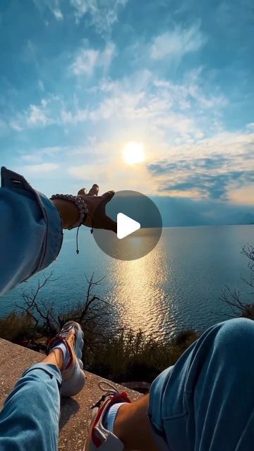 the person is taking a photo with their cell phone while sitting on top of a cliff