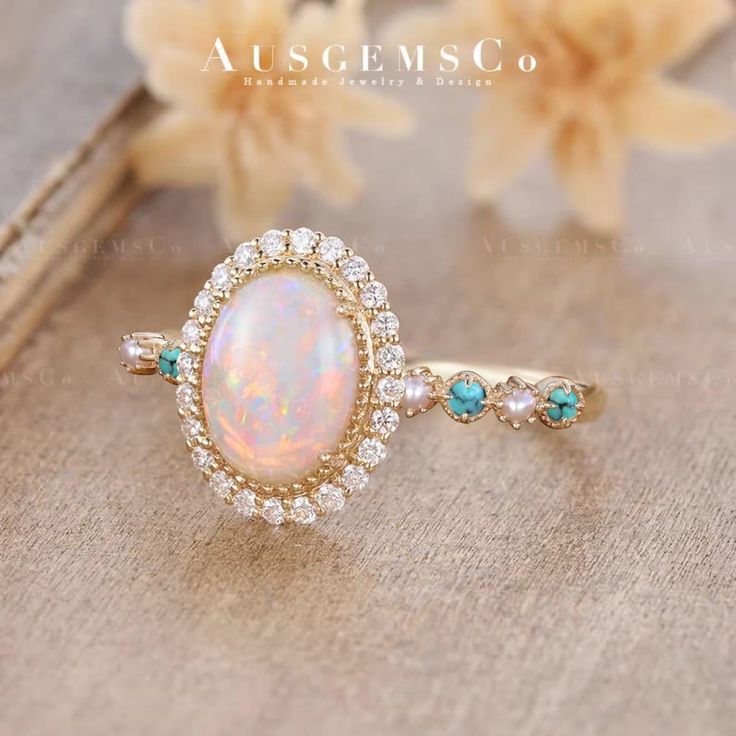 an opalite and diamond ring sits on top of a book with flowers in the background