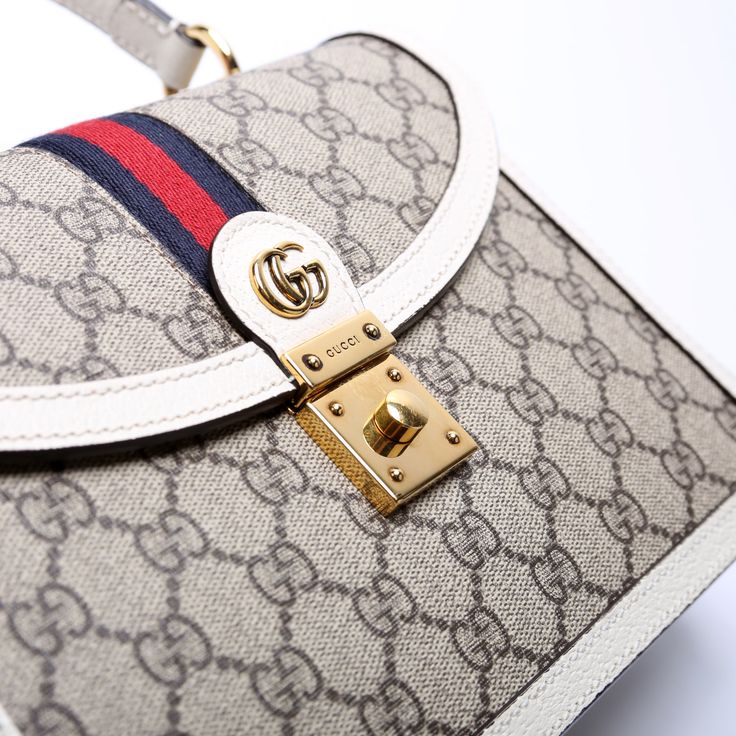 This Gucci Ophidia Small Top Handle Bag . The exterior is in the classic Gucci GG Supreme coated canvas. Condition: Very Good Serial Number: 651055 520981 Color: Tan and White Exterior: The exterior coated canvas is free from any rips or cracks. The corners show minor wear. Handle: The leather handles are free from any major signs of wear. Strap: The shoulder strapis free from wear. The strap has embossed initials. Hardware: The clasp closure has minor scratches. Interior: The interior features one zipper pocket and one open pocket. The interior is clean and free of any major signs of wear. Dimensions: L: 9.75" / H: 6.75" / D: 3.5" Handle Drop: 4" Strap Drop: 19" (Adjustable / Removable) Not Included: Original Dust BagFree delivery over $100 | Delivery 5-8 or 10-15 working days Please note High-end Coated Canvas Bag With Detachable Handle, Luxury Crossbody Bag In Signature Coated Canvas, High-end Bag With Detachable Handle In Coated Canvas, Luxury Signature Coated Canvas Crossbody Bag, Signature Coated Canvas Top Handle Shoulder Bag, Designer Coated Canvas Bag With Detachable Strap, Designer Bags With Detachable Strap In Coated Canvas, High-end Beige Monogram Canvas Bag, Designer Crossbody Bag In Signature Coated Canvas