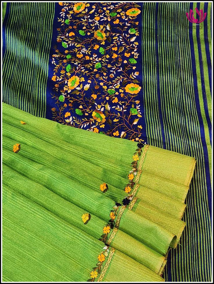 This elegant cotton jute silk saree in parrot green features a contrast blue pallu and border decorated with hand embroidered floral designs. The body of the saree is also adorned with hand embroidered floral designs for a timeless, sophisticated look. Its unique color combination and matching blouse piece in blue with hand embroidery on the sleeves make this saree truly special. Please note: Color may vary slightly from the picture. Thread knots ,Thread pulls and minor inconsistencies are chara Green Slub Silk Traditional Wear With Resham Embroidery, Green Cotton Silk Traditional Wear With Resham Embroidery, Designer Green Slub Silk Dupatta, Embroidered Green Slub Silk Traditional Wear, Green Cotton Silk Traditional Wear With Embroidered Border, Green Embroidered Slub Silk Traditional Wear, Green Traditional Wear With Embroidered Cotton Silk, Pista Green Embroidered Slub Silk Dupatta, Pista Green Cotton Silk Saree With Resham Embroidery