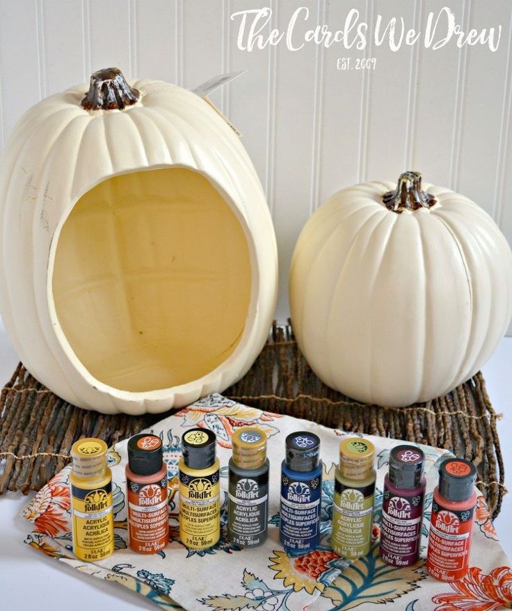 two white pumpkins sitting on top of a table next to some bottles and paint