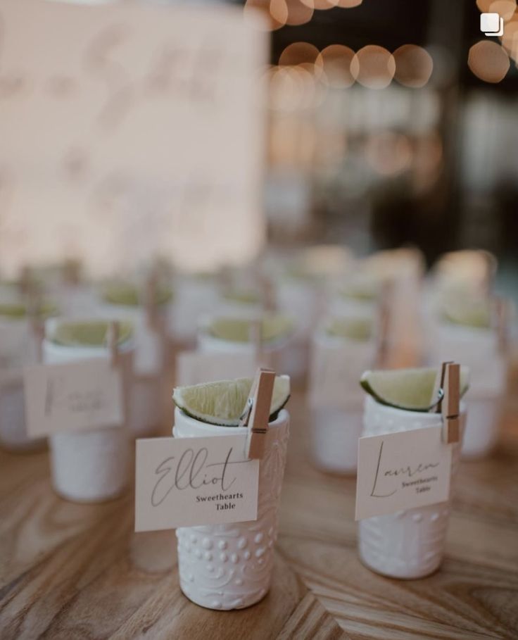 small white cups with limes in them on a wooden table and lights behind them