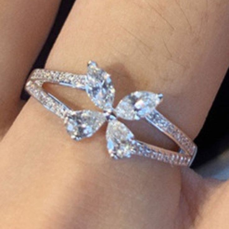 a close up of a person's hand wearing a ring with three pear shaped diamonds on it