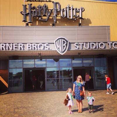 a woman and two children standing in front of a harry potter studio