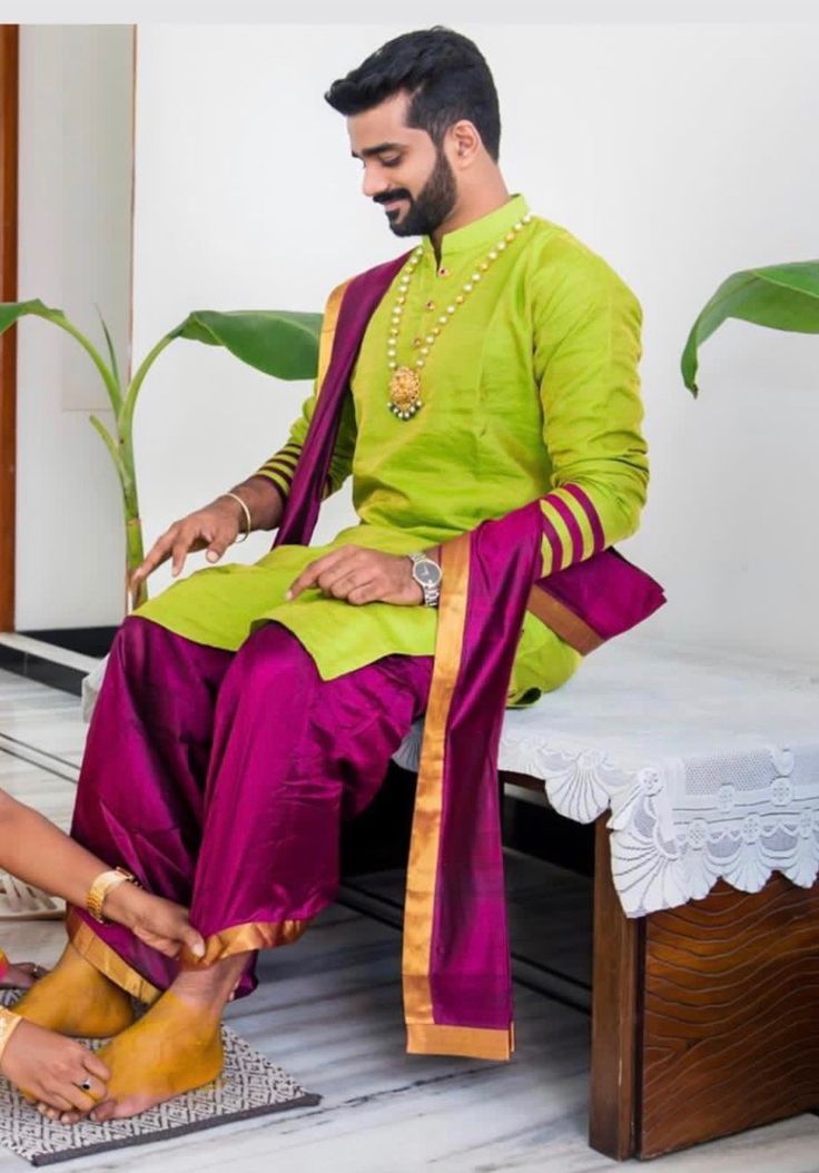 a man sitting next to a woman on top of a wooden bench in front of a potted plant