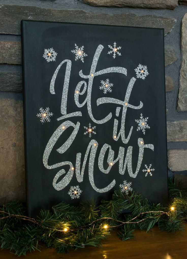 a chalkboard sign that says let it snow on top of a mantle with christmas lights