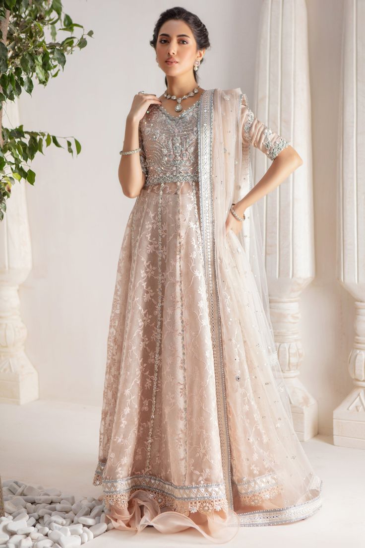 Step up your festive dressing game with our beautifully crafted kalidar over a canvas of stunning embroidered organza, heavily embellished with sequins, beads, crystals, neckline and sleeves beautifully adorned with gorgeous zardozi, mirror work & Resham thread work. Stunning hand-made stylized tassel details at back. This stunning multi panel kalidar is offset with jamawar Lehanga with gorgeous ruffle details & net dupatta featuring sequins & mirror motifs and chan, trimmed with mirror embroidered borders , a Must- have wardrobe staple to carry all Wedding Festivities in effortless style. Shirt Fabric: Pure embroidered Organza & Silk Net Lehanga Fabric: Jamawar Dupatta Fabric: French Net Color: Shell Pink This outfit is only available in Custom size, once order is placed design team will Unstitched Embellished Chinon Dress, Embellished Party Wear Gown For Eid, Embellished Party Gown For Eid, Festive Chinon Anarkali Set With Intricate Embroidery, Raw Silk Anarkali Set With Dabka Work For Reception, Embellished Chinon Floor-length Dress, Designer Embellished Chinon Dresses, Designer Wear Embellished Chinon Dresses, Unstitched Embellished Gown For Eid