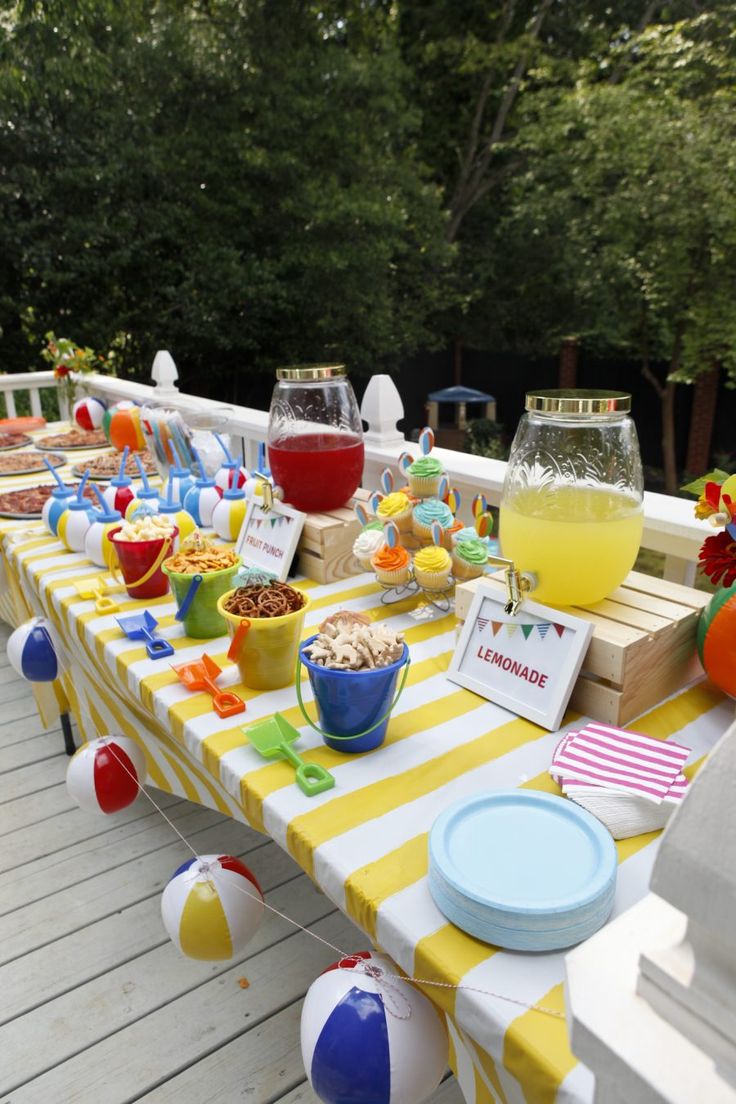 an outdoor party with yellow and white striped table cloths, plates, cups and bowls filled with food