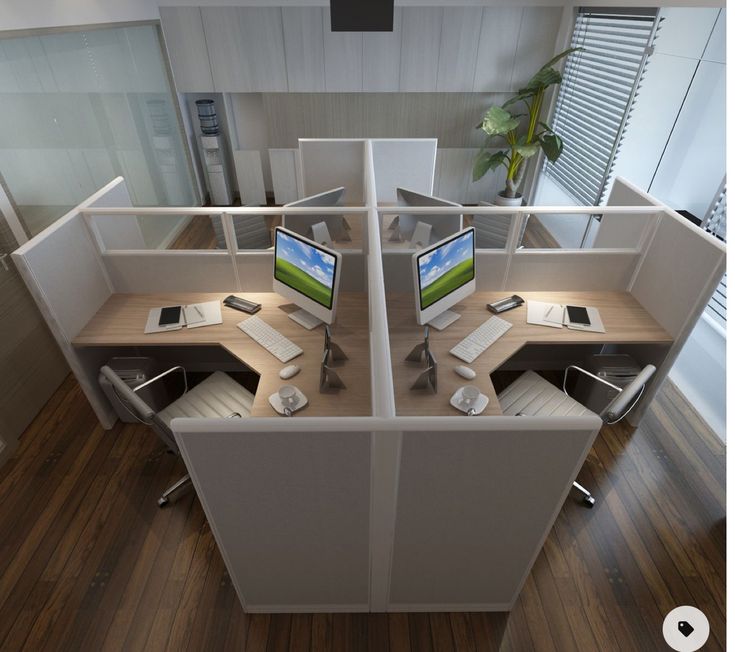 an office cubicle with two computer screens on the desks and one desktop monitor