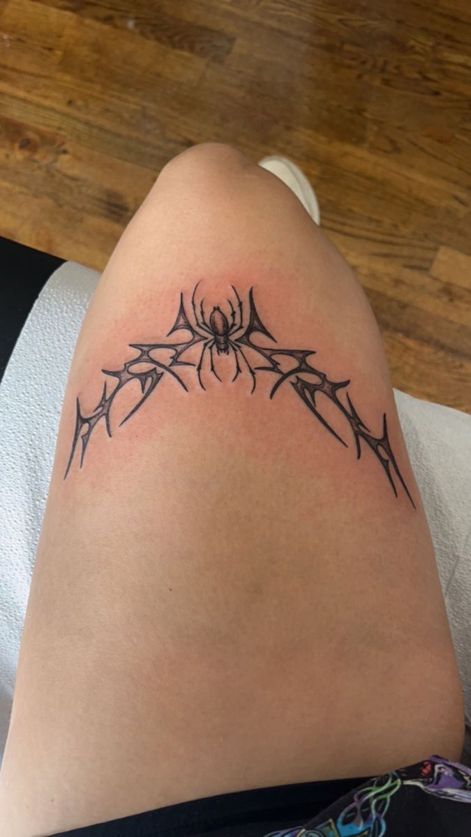 a spider web tattoo on the back of a woman's thigh