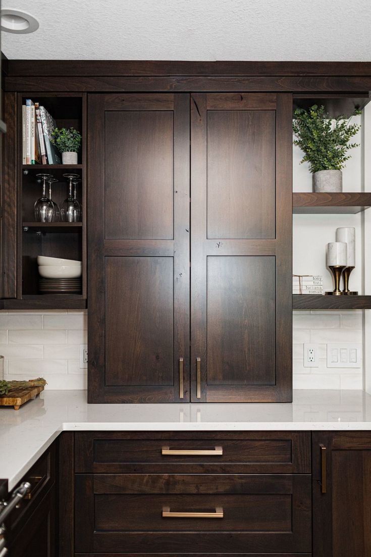 a kitchen with dark wood cabinets and white counter tops, along with open shelving