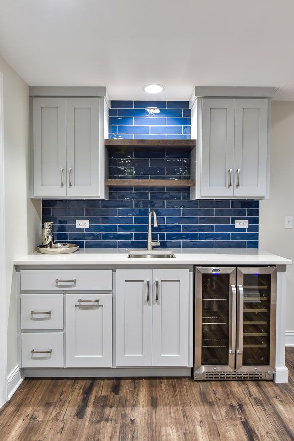 a kitchen with white cabinets and blue tile backsplash