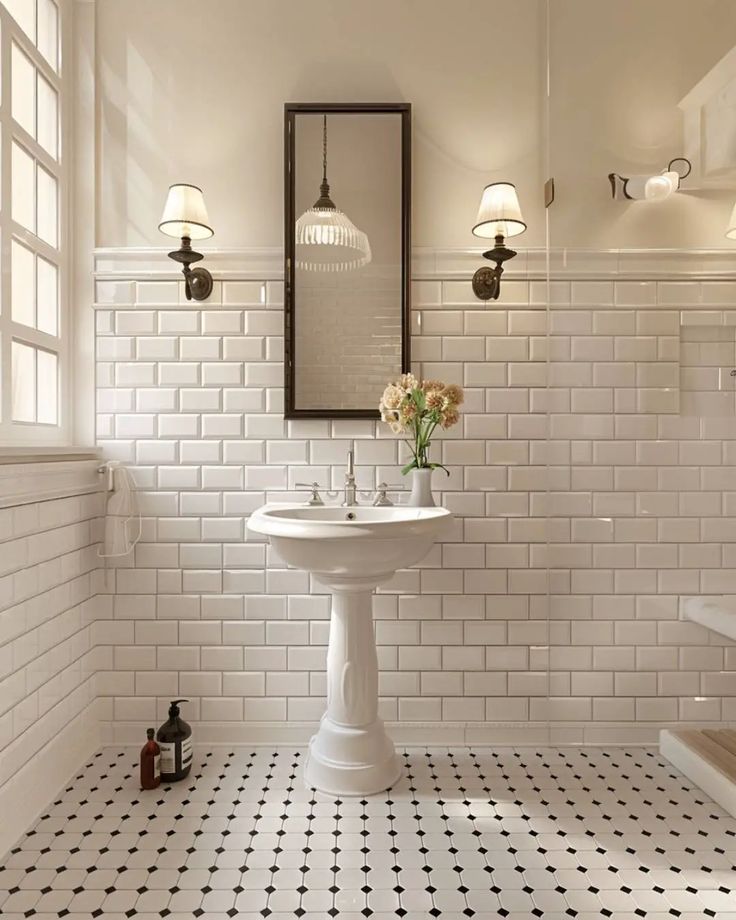 a white bathroom with black and white tile flooring, a pedestal sink and mirror