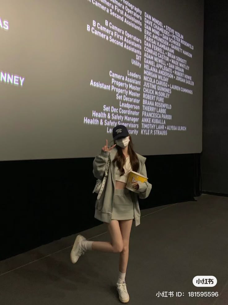 a woman is walking down the runway in front of a screen with words on it