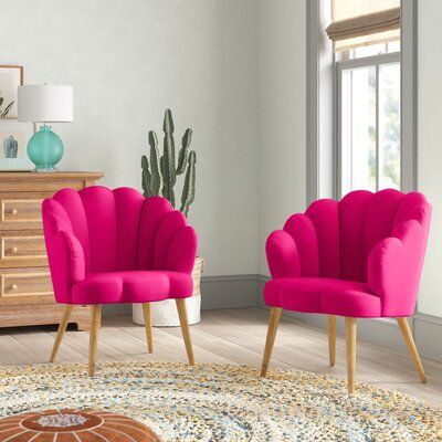 two pink chairs sitting in front of a window on top of a wooden floor next to a potted plant