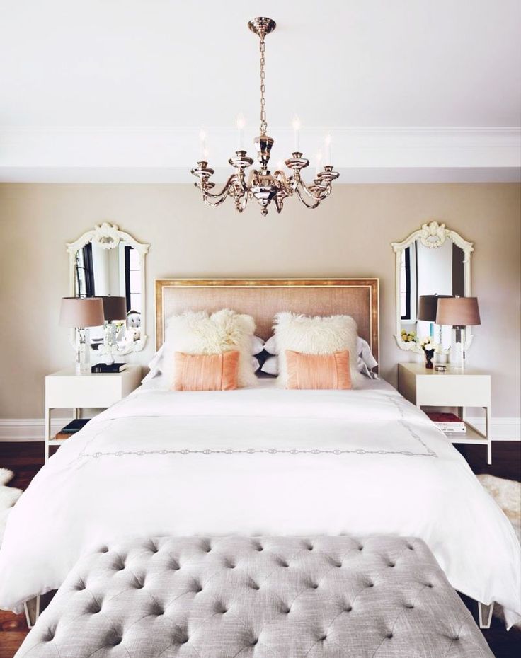 a white bed sitting under a chandelier in a bedroom