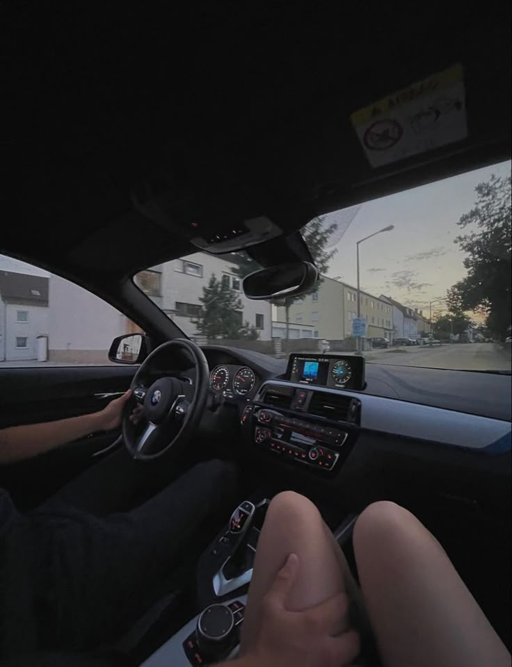 a man driving a car down a street next to another person sitting in the driver's seat