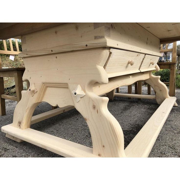 a picnic table made out of wooden planks with benches in the back ground behind it