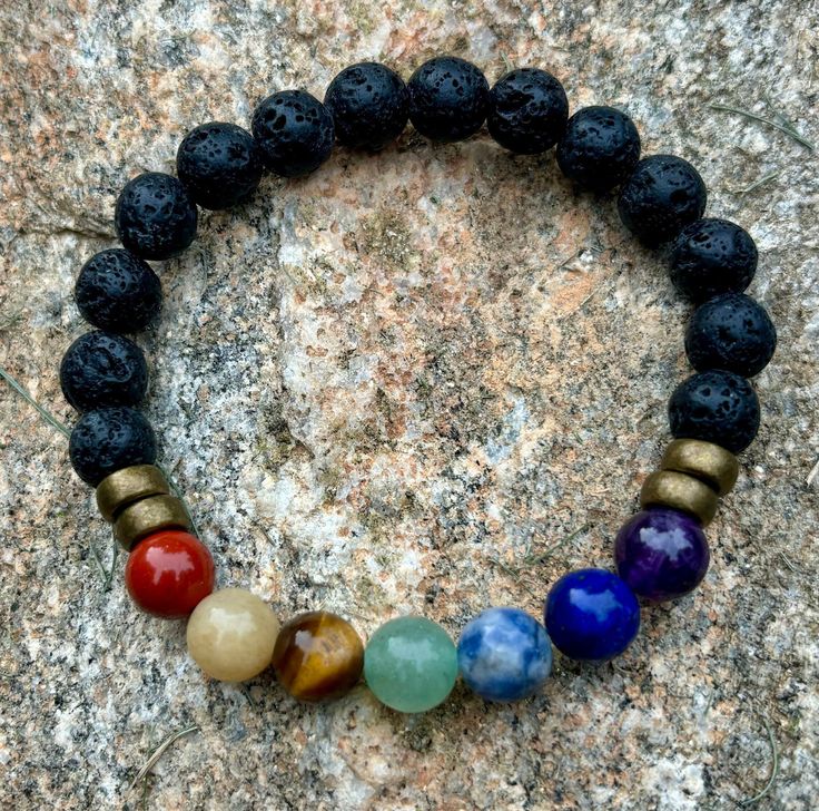 Enhance your energy and style with our Handmade Unisex Chakra Bracelet! Crafted with premium gemstones and 8mm black lava stone beads, this unique piece offers both beauty and balance. The clear stretch cord ensures a comfortable fit on an average wrist size of 7 inches.  Why You'll Love It: - **Holistic Healing Each gemstone is carefully selected to align and balance your chakras, promoting inner peace and well-being. - **Quality Craftsmanship Handmade in the USA with meticulous attention to de Spiritual Lava Stone Bracelets With 8mm Beads, Round Beads Bracelet With Natural Lava Stone, Spiritual Lava Stone Beaded Bracelets With 8mm Beads, Healing Bracelet With Gemstone Beads And Lava Stone, Spiritual Lava Stone Stretch Bracelet With Natural Stones, Healing Lava Stone Bracelets With Gemstone Beads, Healing Lava Stone Beaded Bracelets With Round Beads, Black Lava Stone Spiritual Beaded Bracelets, Black Lava Stone Bracelets With Gemstone Beads