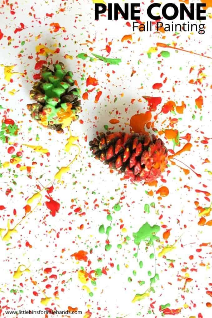 two pine cones sitting on top of paint splattered paper with the words pine cone fall painting